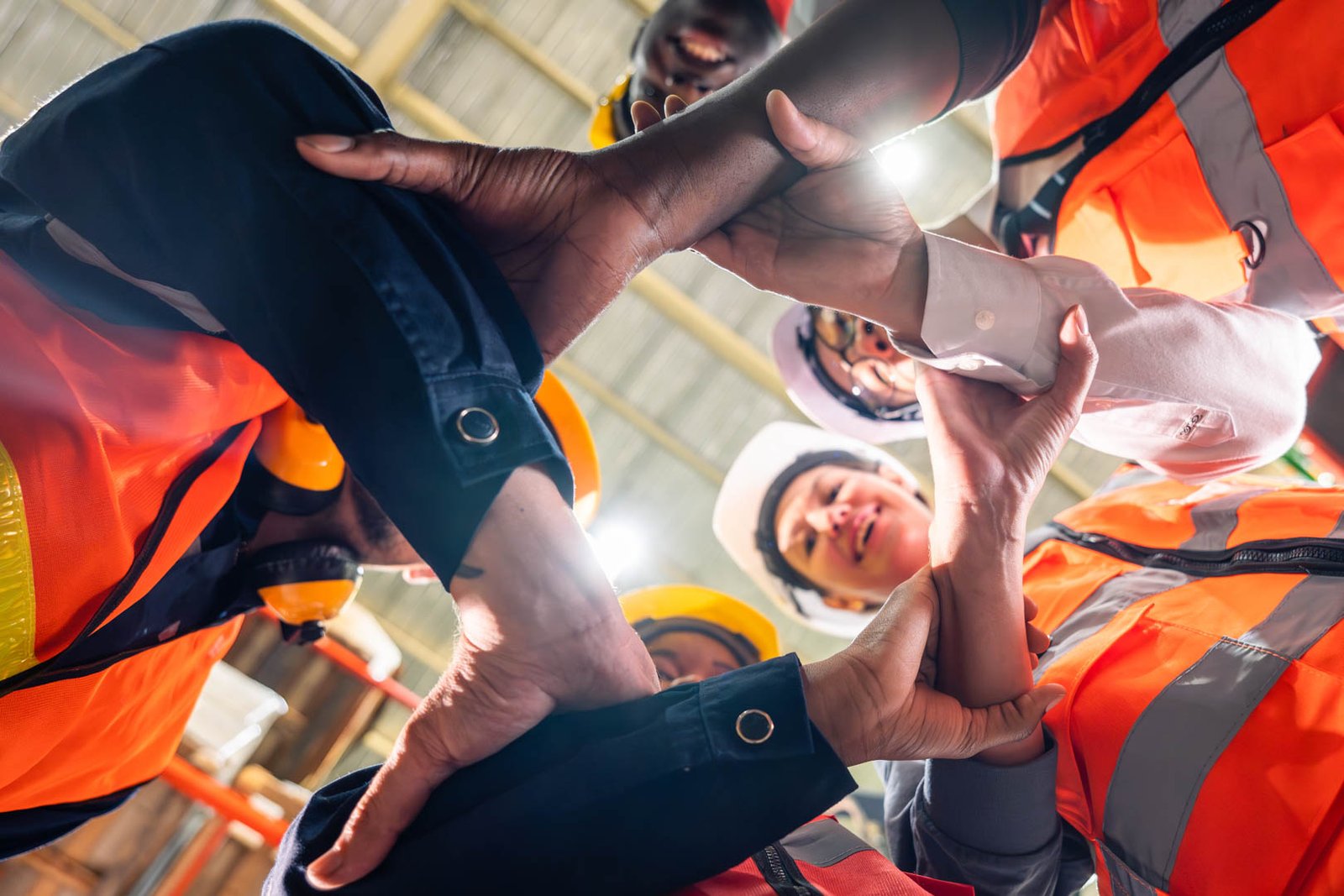 Group of diverse industrial worker work together in manufacturing plant. Attractive industry factory engineer people stack hands to motivate and working as unity teamwork at manufactory warehouse.